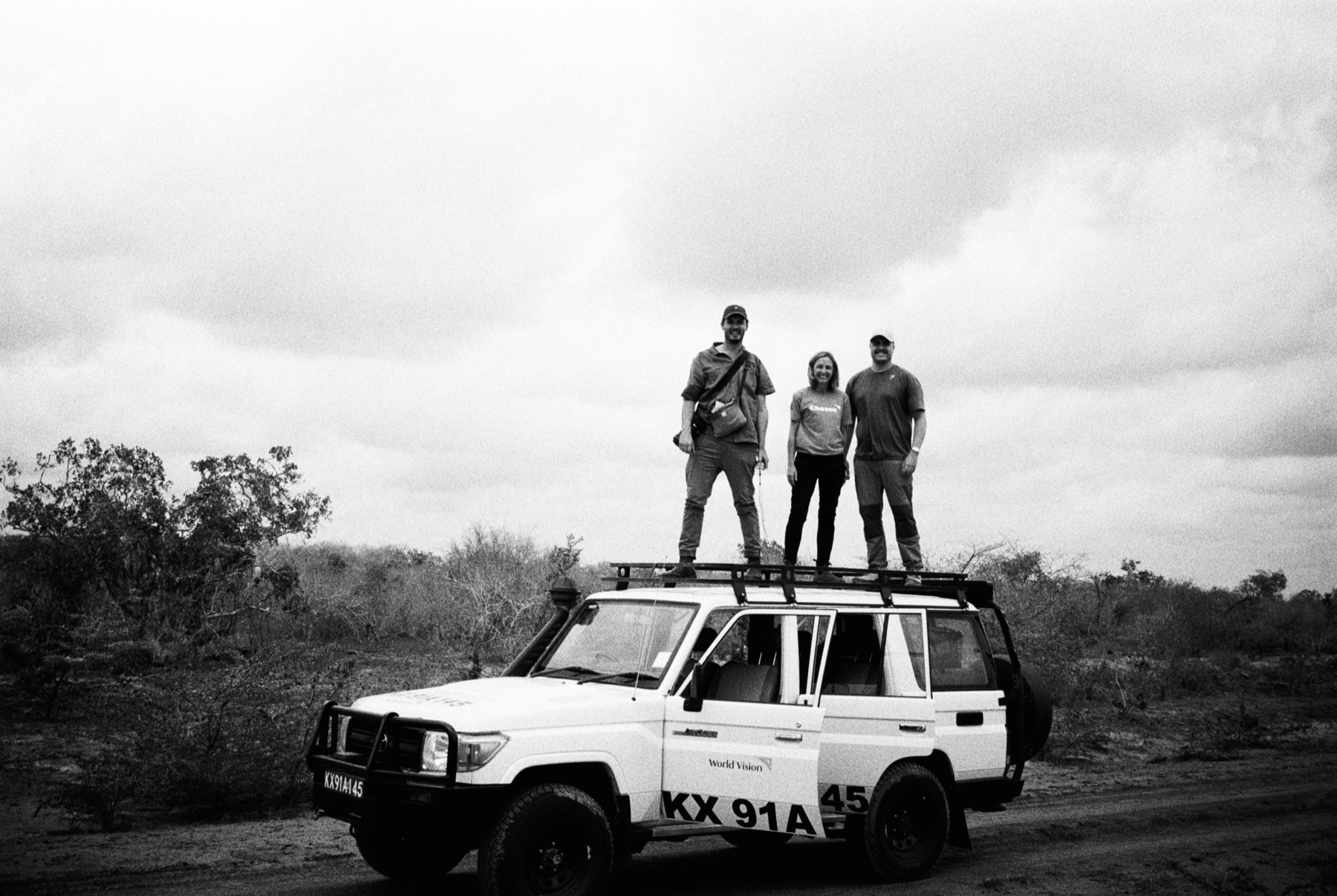 The Communitas crew standing on a Land Cruiser in rural Kenya, Matt Benn in the middle, black and white